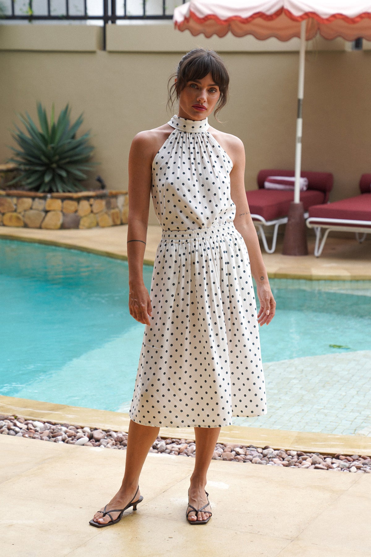 Woman in a polka dot dress standing by a poolside