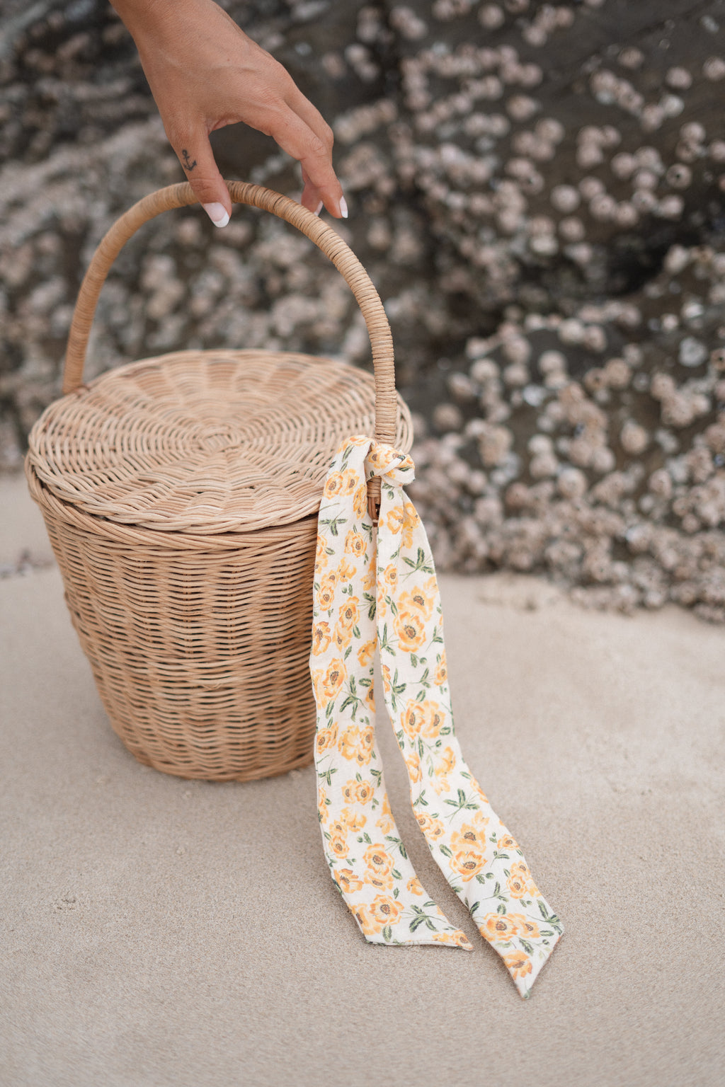 woven round picnic basket with a floral material ribbon tied to its handle