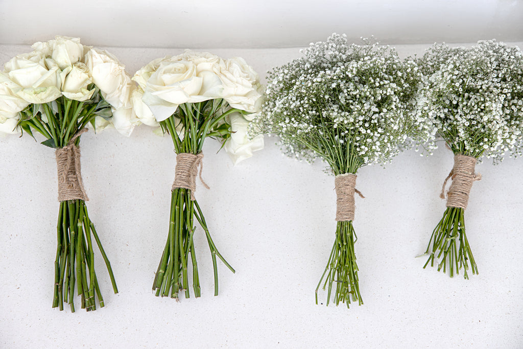 Four bridal bouquets with white flowers sitting on a bench, view from above