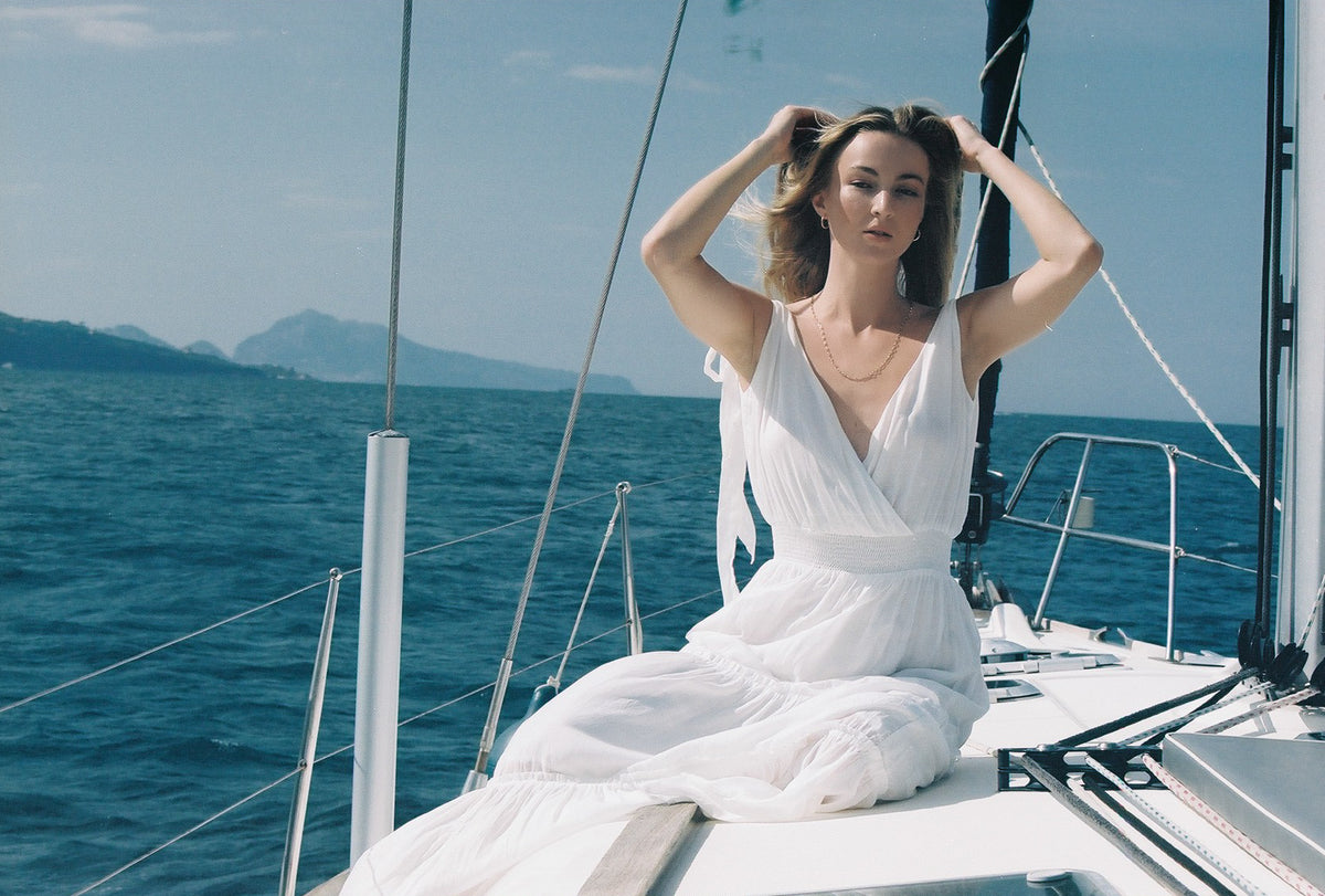 Woman wearing white dress on the bow of a yacht