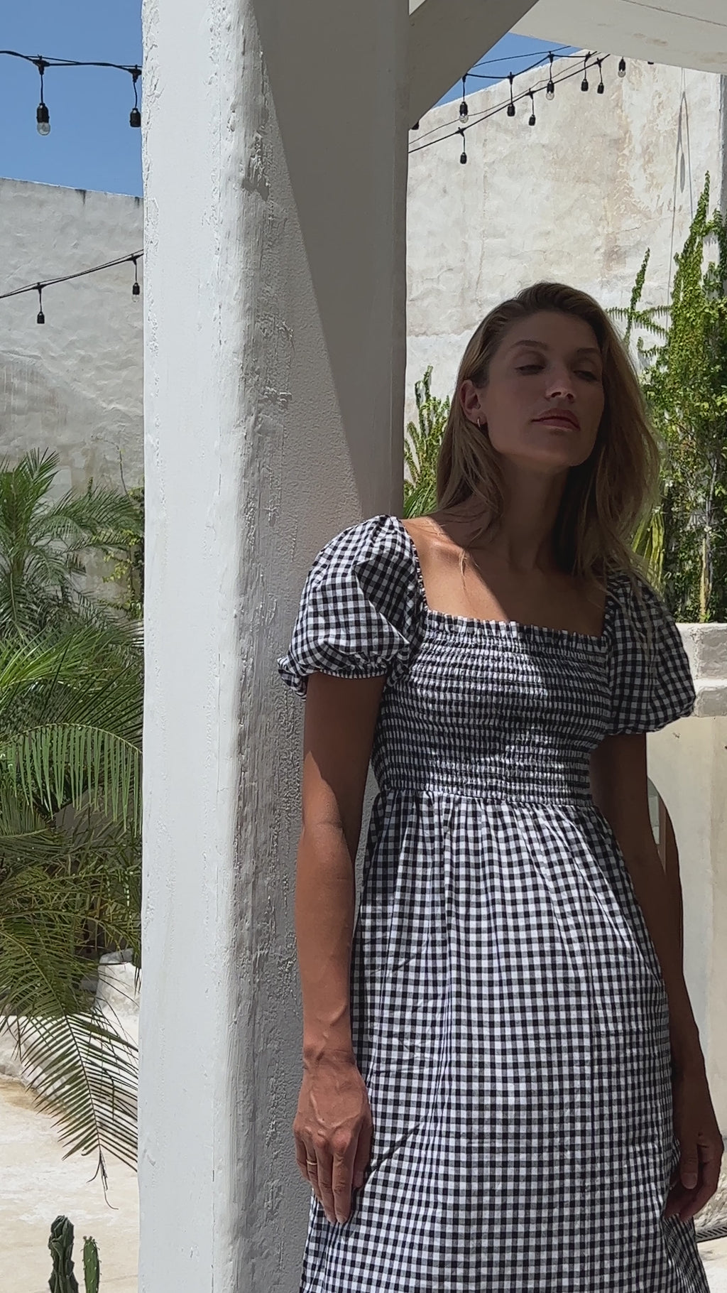 Woman wearing square neck gingham midi dress standing on the porch