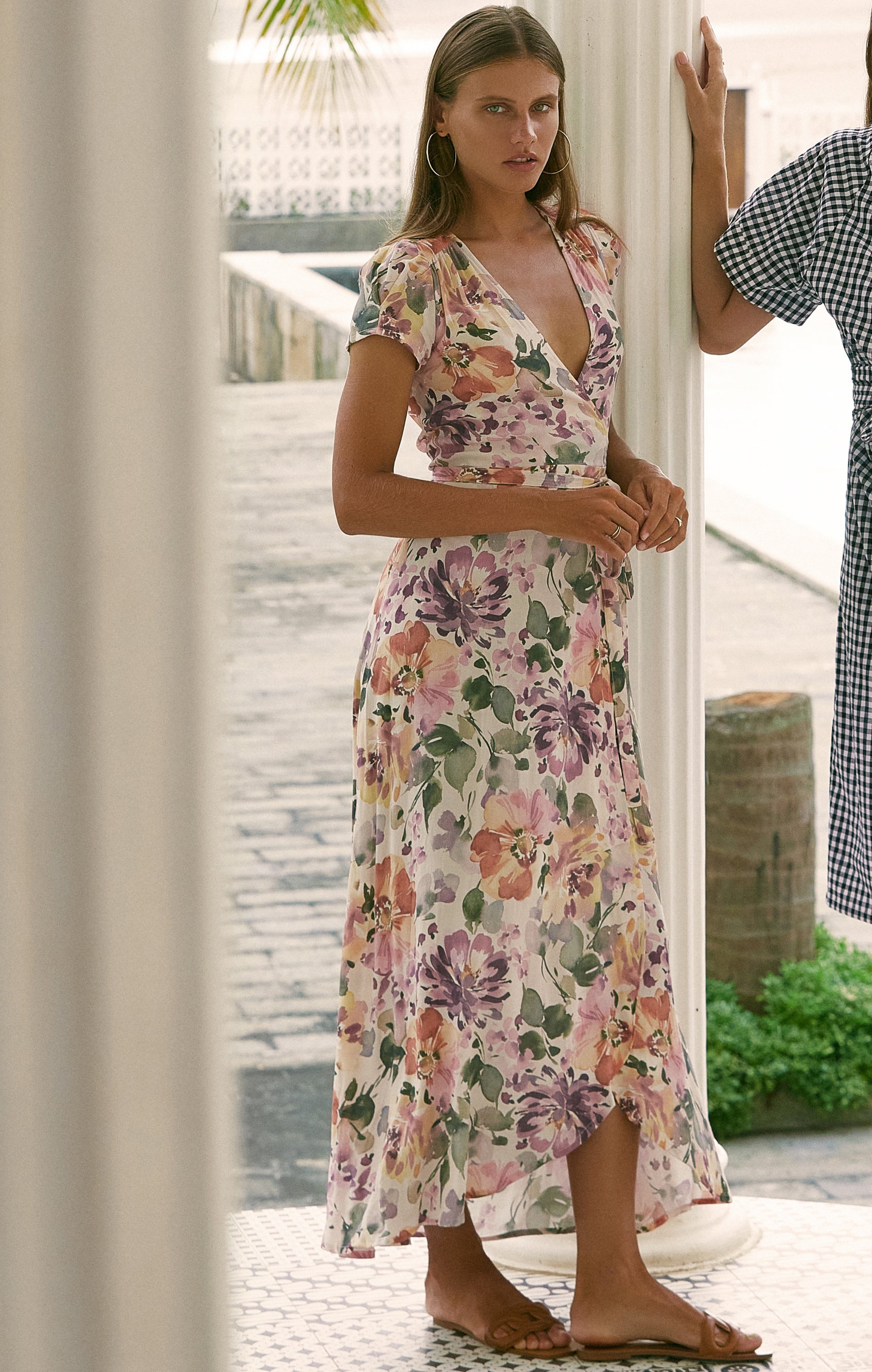 Woman wearing maxi floral wrap dress standing on a porch