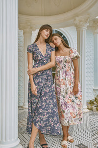 Two woman leaning on each other wearing floral printed summer dress