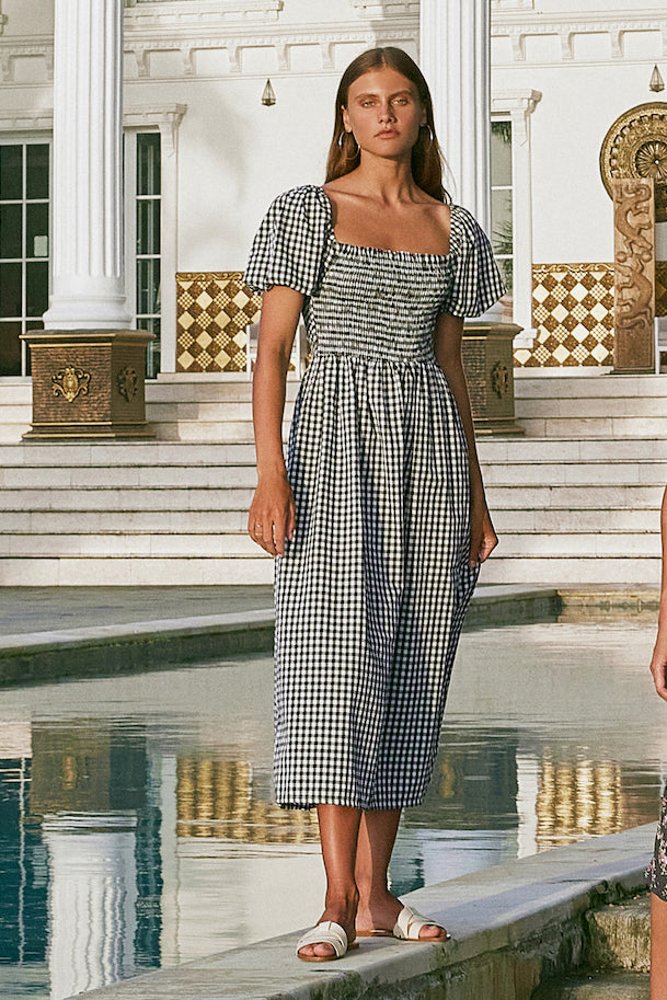 Woman wearing square neck gingham midi dress standing next to the pool