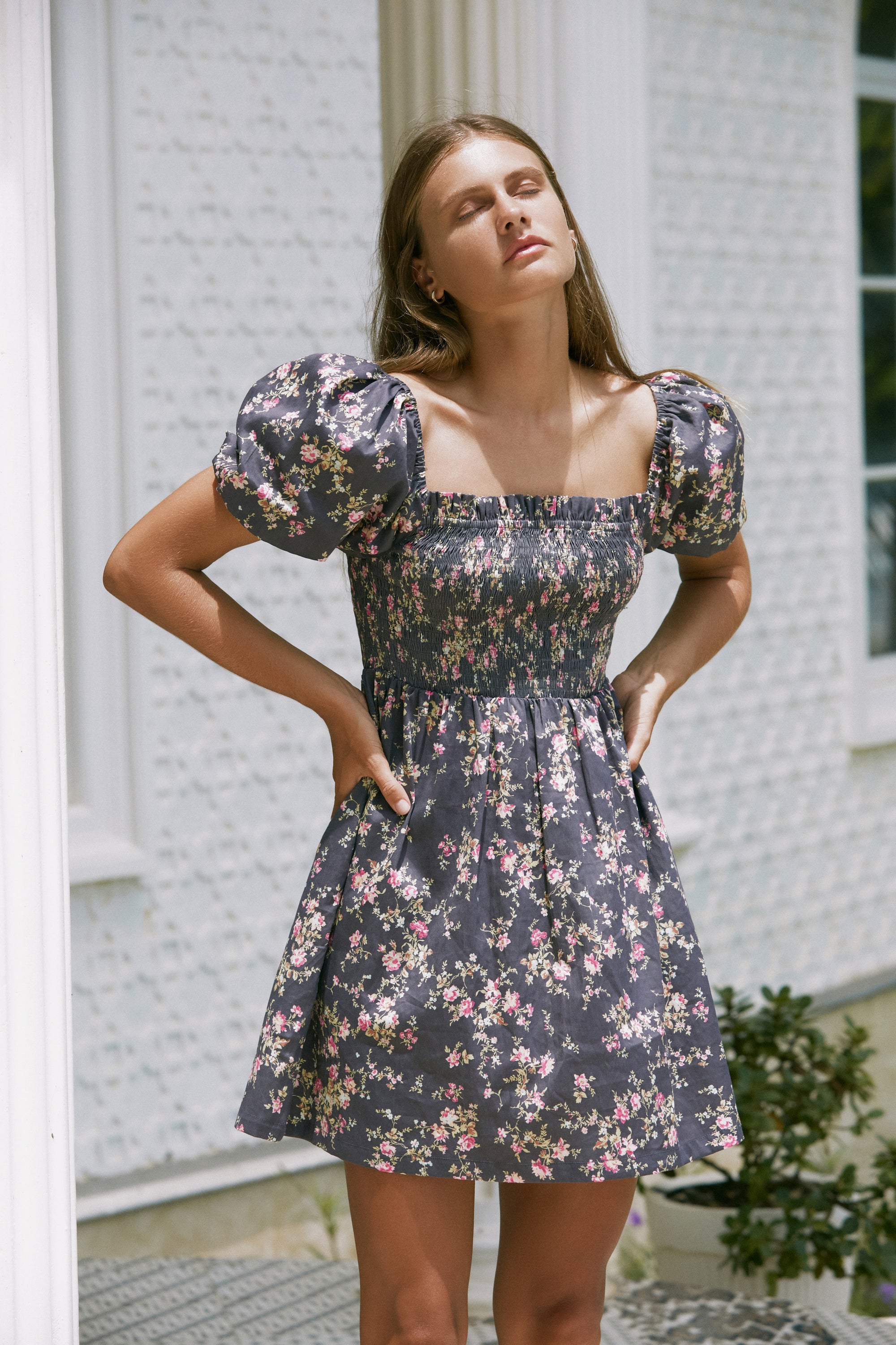 Woman wearing floral print summer dress with her both hands on her waist