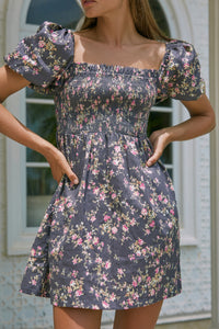 Close up view of a woman wearing floral print summer dress with her both hands on her waist