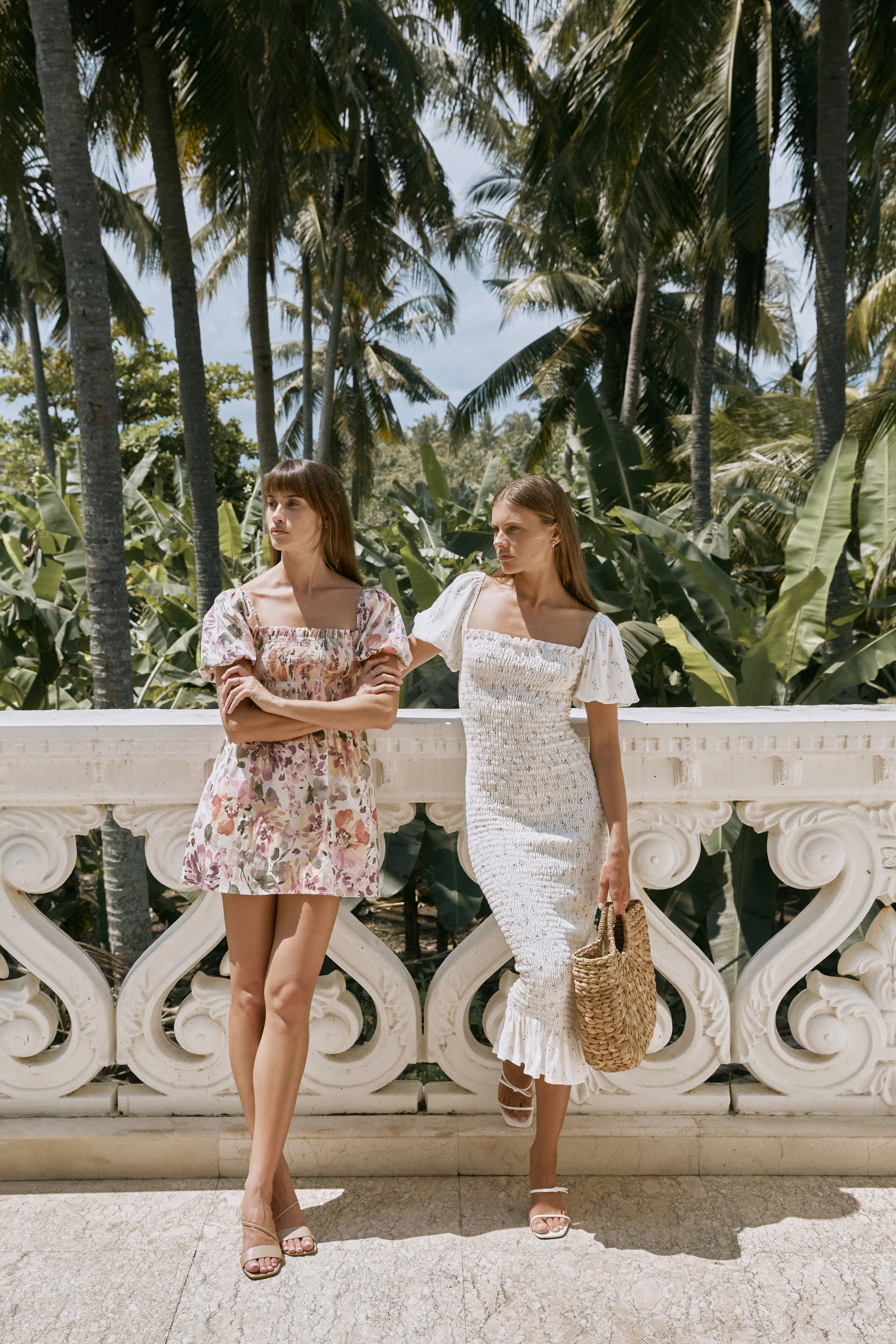 Two women with brown hair wearing floral print summer dresses