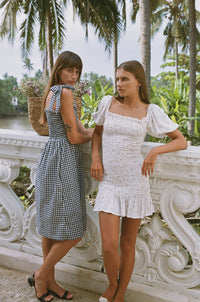 Two women wearing shirred dresses standing in front of a white balustrade