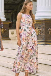 Side view of woman with dark hair wearing a floral print maxi dress with boat neck