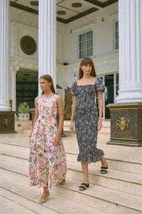 Two women walking down stairs wearing floral print dresses