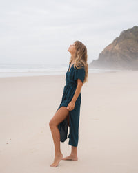 Girl showing leg on a beach wearing teal dress
