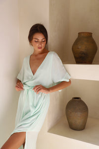 Girl leaning on a wall wearing Aqua wrap dress