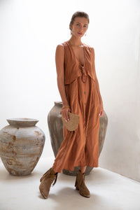 woman with dark hair posing in a rust coloured bridemaid dress
